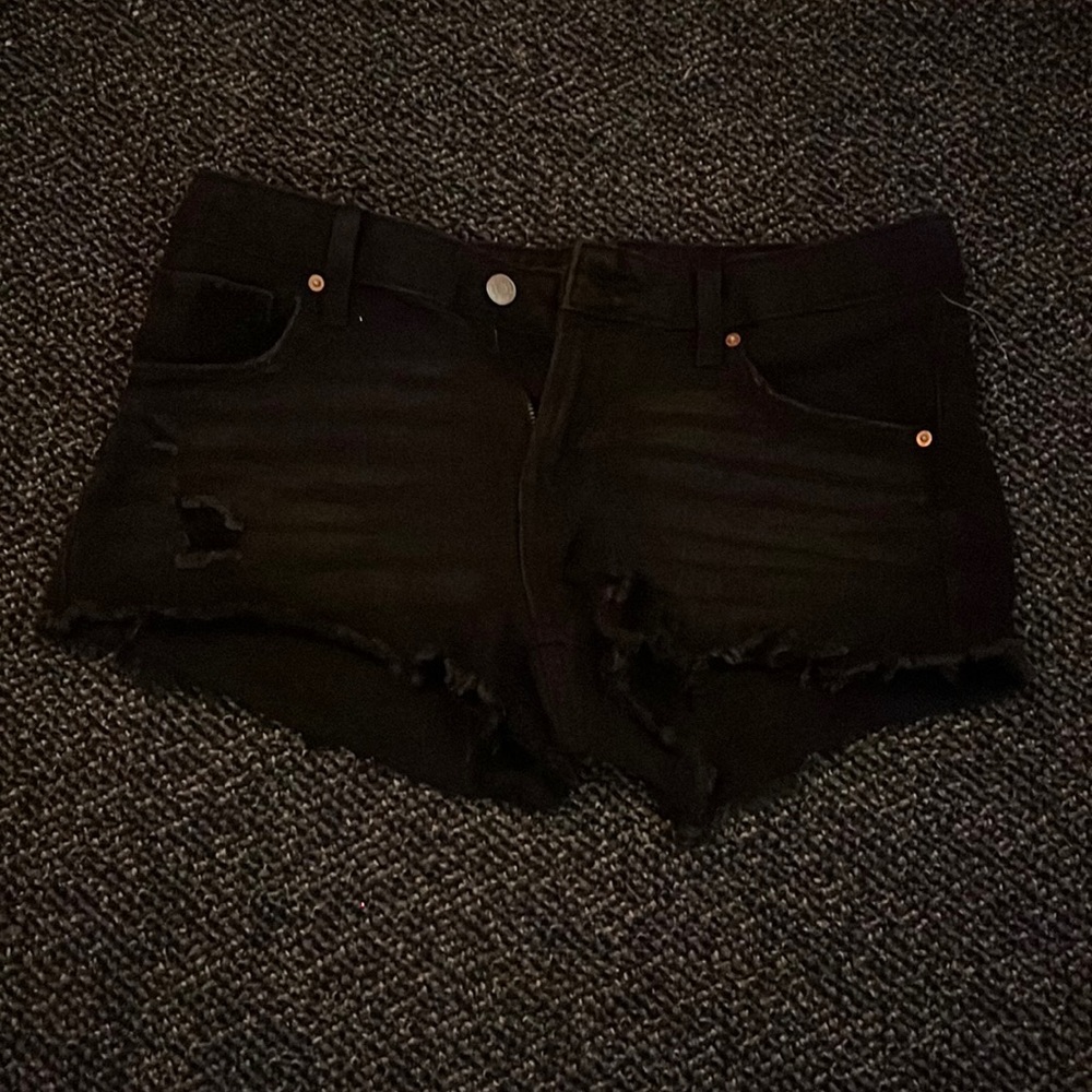 Short black jean shorts with a rip and “cut off” bottom look.